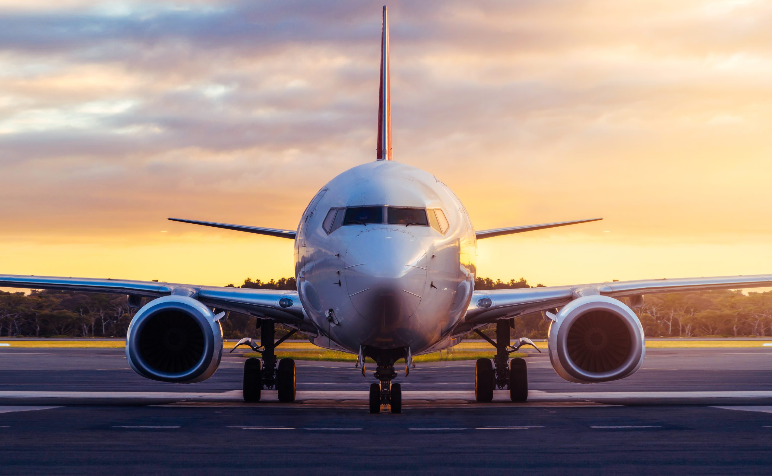 Airplane on runway at sunset facing the viewer