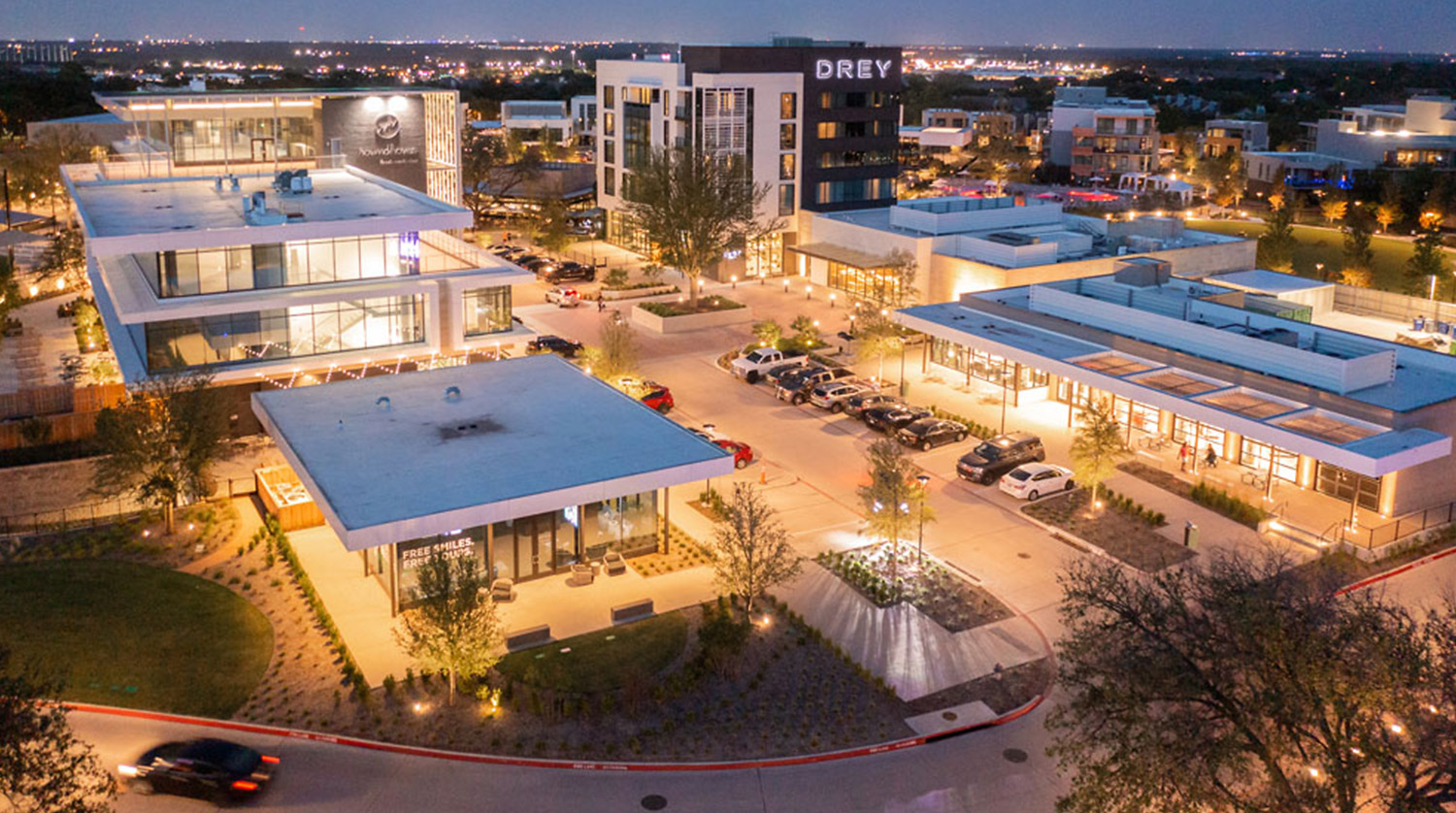 Buildings at evening time with lights on as seen from a drone.